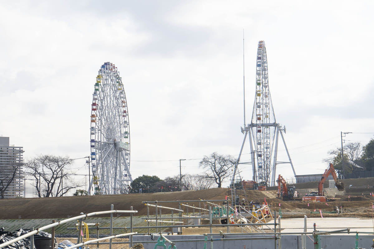現場からはよみうりランドの観覧車が見える。現在は新旧観覧者が並んでいる