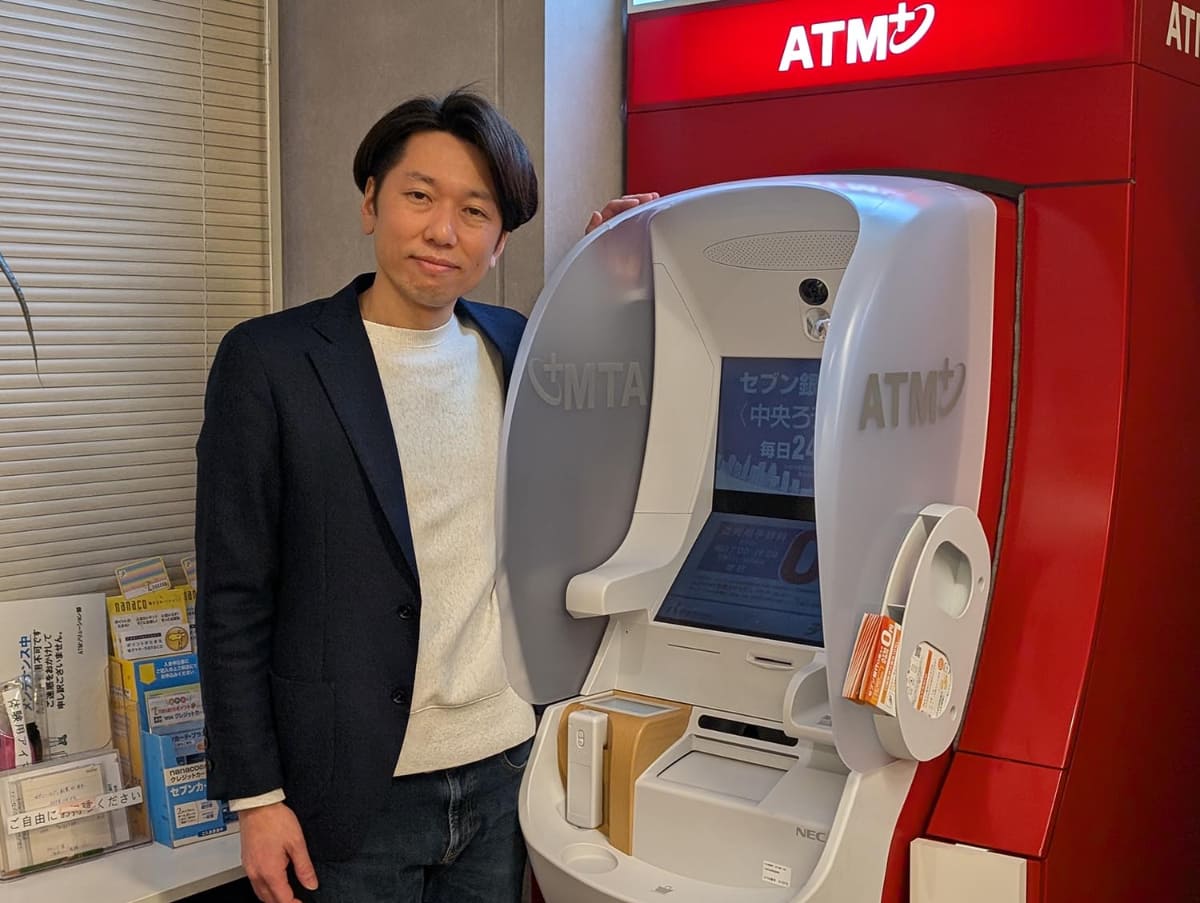 セブン銀行 ATM＋企画部長兼グループ長の柏熊俊克氏。商業施設設置型の第4世代ATMとともに