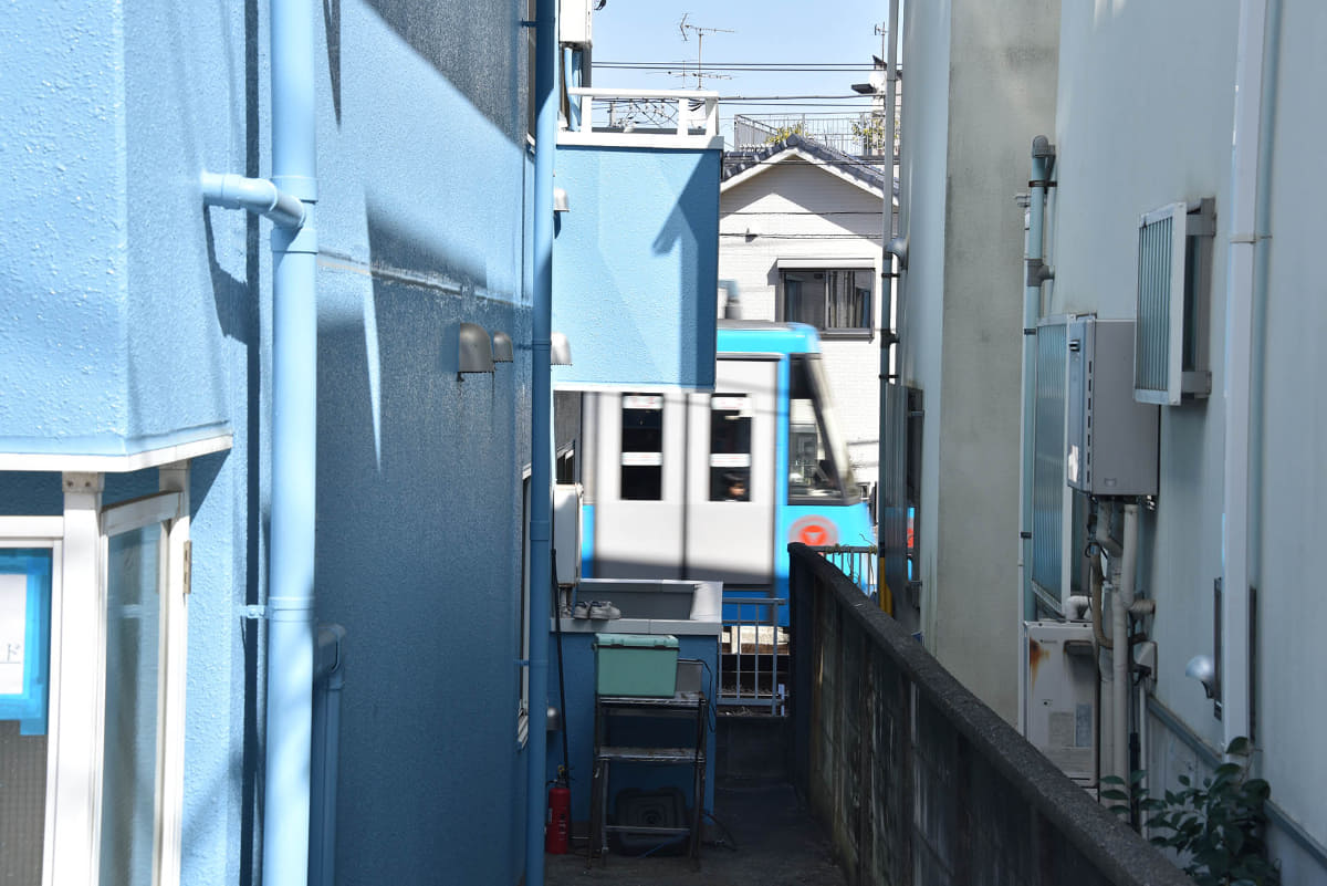 家と家と間から世田谷線の電車が見える