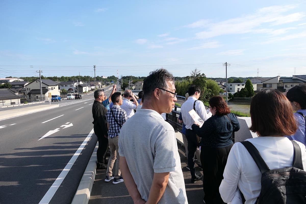 土地造成が始まったばかりの場所を撮影する取材陣。左側にJ-PARCがあり、右側へニュートリノが通る。1秒に一回程度、瞬間的に流れる川のようなイメージが実際と近いそうだ