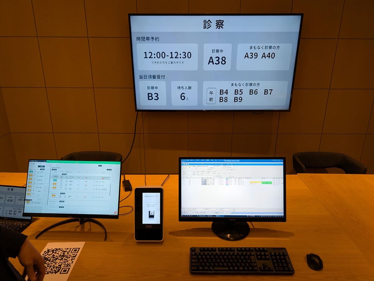 ウィーメックスのシステムは医療機関に設置されるシステムを模したものになる。オンライン資格確認のための顔認証付きカードリーダーと電子カルテ情報を見られる受付システム、患者に待合情報を伝えるディスプレイで構成される