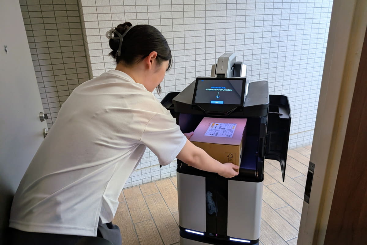 配送ロボットが宅配ボックスから荷物を取り出し、対面配達を行なう様子