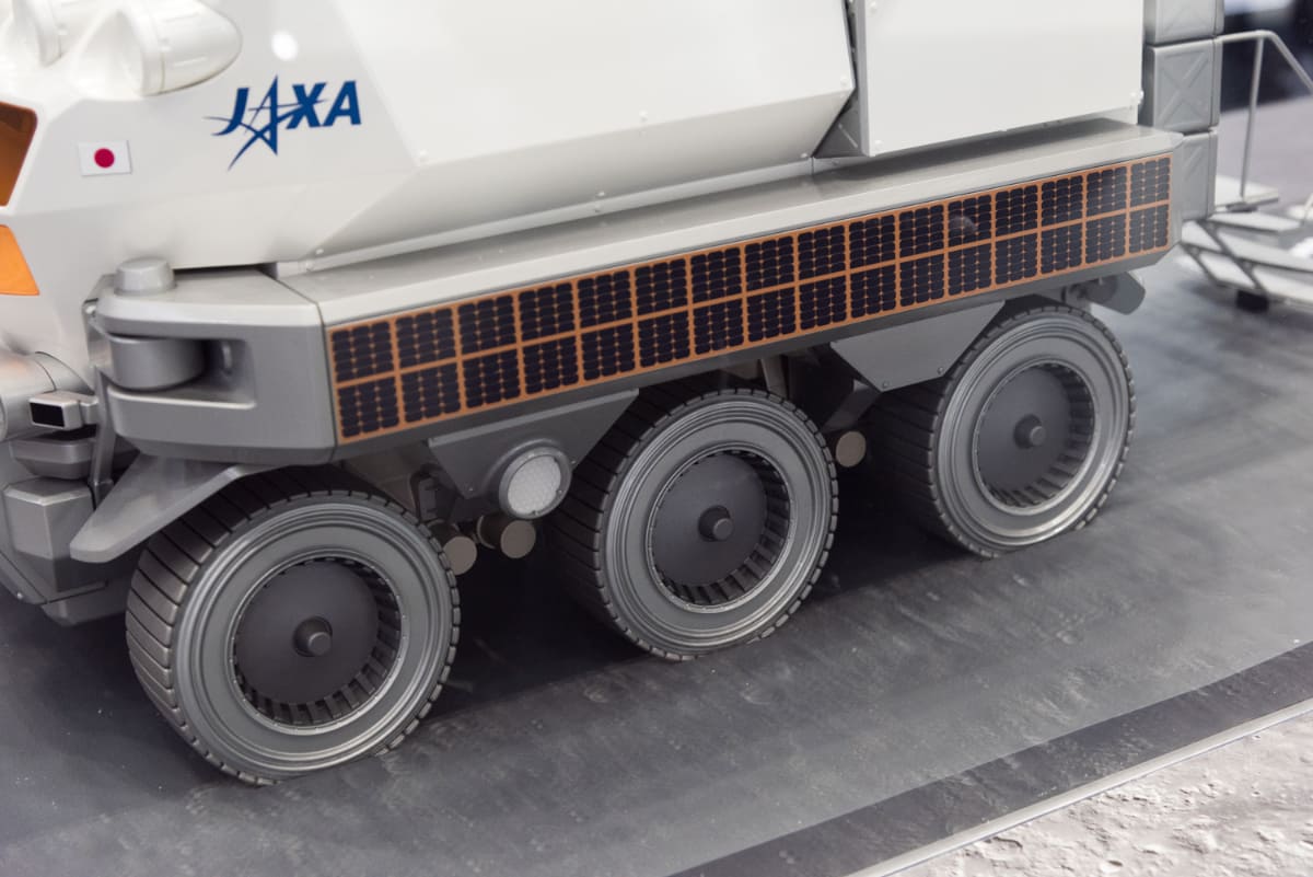 JAXA/トヨタで開発中の有人与圧ローバの模型。6輪で走行し、与圧キャビン内で宇宙飛行士は宇宙服を脱いだシャツ姿で生活できる機能を備えています。走行性能やエネルギーを供給する展開式大型の薄膜太陽電池パネルの展開実験などが地上で続いています(撮影:小林伸)