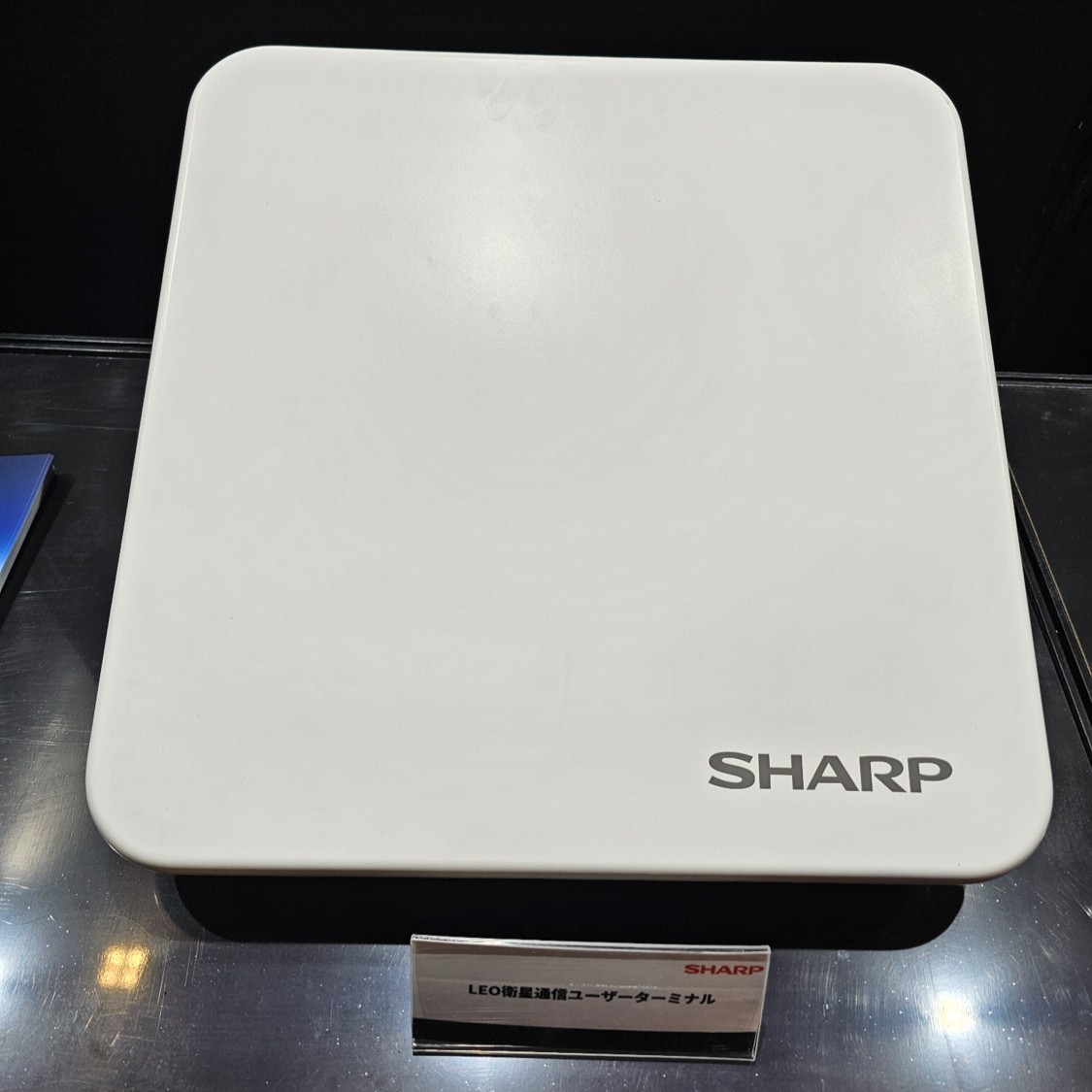 シャープが開発中の5G NTN通信対応 LEO衛星通信ユーザー端末。英OneWeb衛星と通信し、建設機械の遠隔操作を支援します。7kgの大型アンテナを搭載した建機を使用し、日本と台湾を結ぶ遠隔操作実証を2026年に計画中とのこと(撮影:秋山文野)