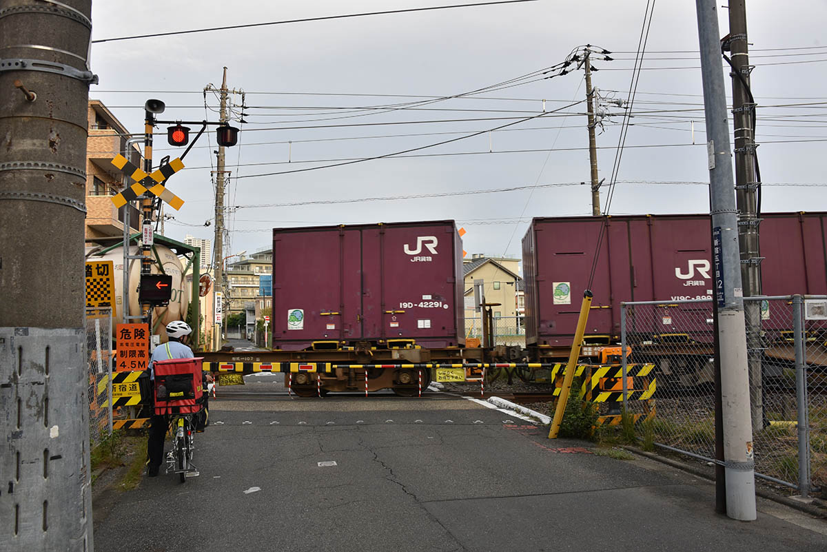 新金貨物線を走る貨物列車。旅客列車より編成が長いため、踏切の遮断時間は長い。写真は国道6号線とは別の踏切