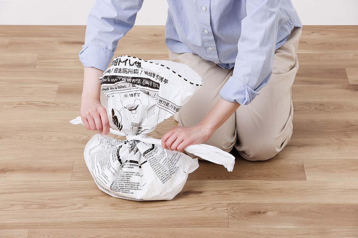 便座に取り付けた本体袋を外し、上部の開口部を切り離して結ぶ