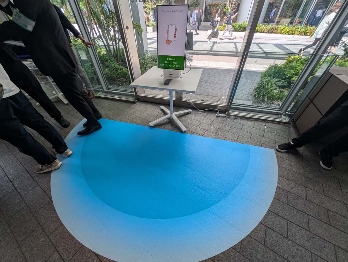 UWB技術を用いた未来の決済体験デモと銘打たれた体験コーナー。濃い半円のエリアに入ってスマートフォンの正面を正確に画面側に向ける必要がある