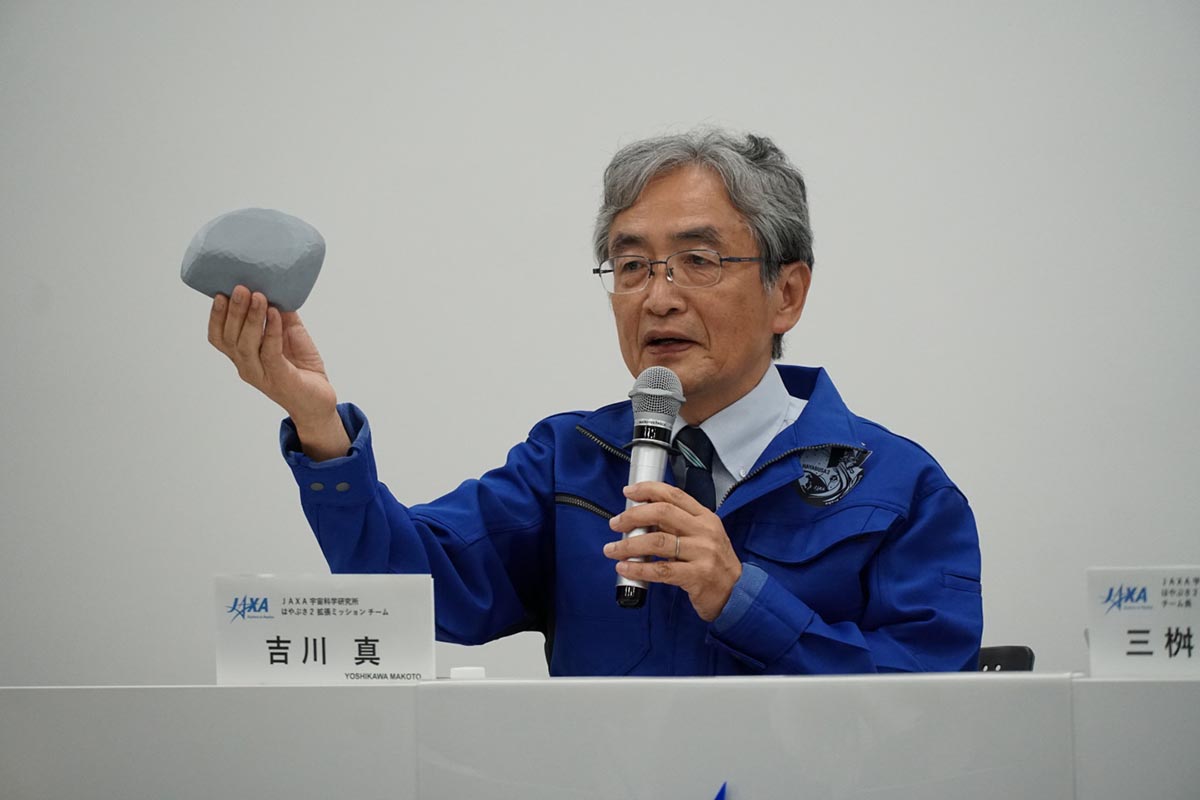 予想されていた小惑星トリフネの予想による模型を手にする吉川真准教授。地上の観測では「細長い」ということしかわからず、くびれを持ったコンタクトバイナリの姿に驚いたという(撮影:秋山文野)