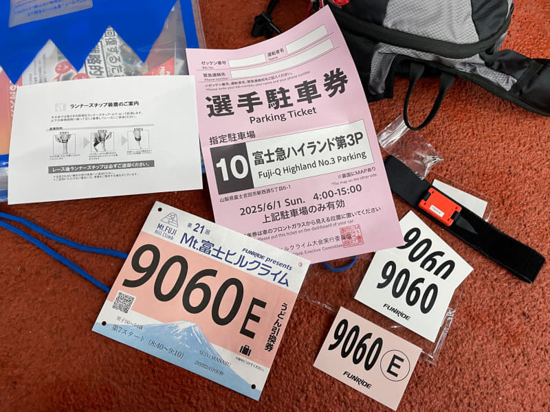 ゼッケンや駐車券など。赤いパーツのついた黒いベルトは計測器。足首に巻いて使う