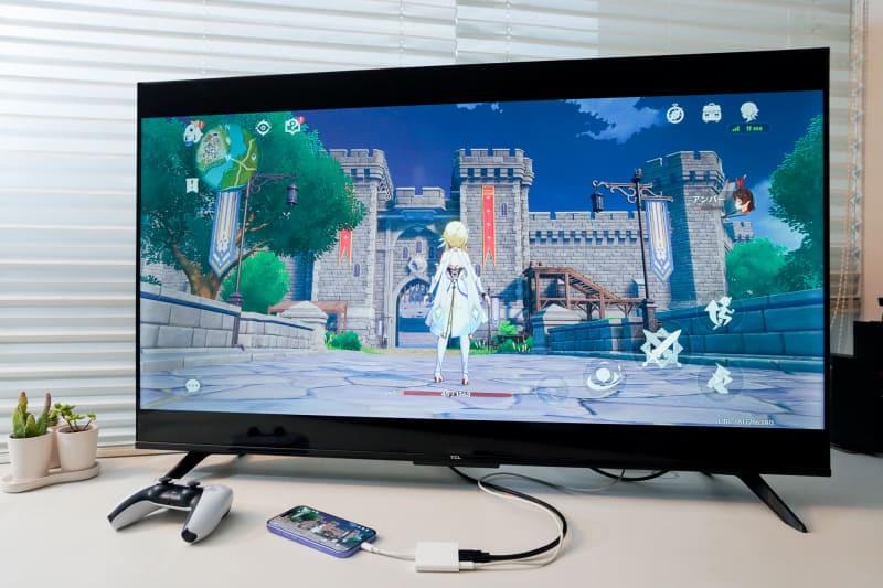 ヨコ画面のスマホゲームなら迫力の大画面でプレイできる。コントローラーを接続して楽しもう。ゲーム画面はオープンワールドRPGの「原神」　© COGNOSPHERE<br><br>※「原神」はコントローラー操作に対応している。チュートリアルまではスマホで操作し、終了すると左上に「パイモン」アイコンが表示されるようになるので、それを開く。設定の［操作］ー［デバイス］で［タッチスクリーン］と［コントローラー］の選択ができる。一度ゲームを終了すると、［タッチスクリーン］に戻るので再度設定が必要になる		スマートフォンのオープンワールドRPG「原神」の画面を、大画面テレビにミラーリングした状態