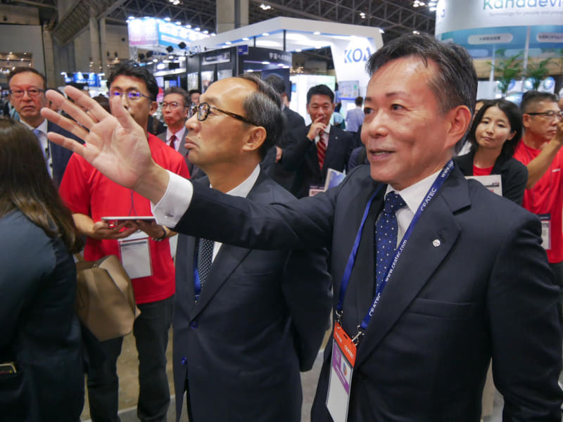 開催初日には日立製作所の德永俊昭社長兼CEO（右）が、日立ブースを訪問した三菱電機の漆間啓社長CEO（左）を案内するシーンも