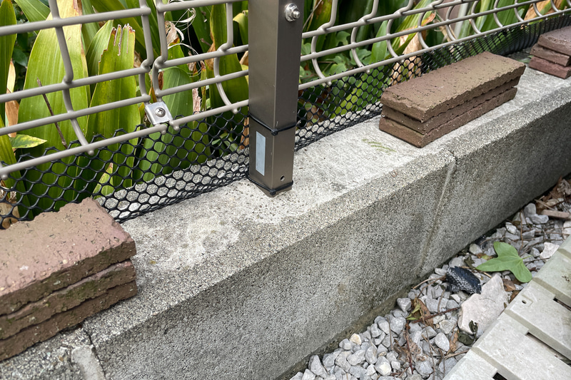 フェンス下の幅に切ってタイラップで固定。ただ、強く押せばめくれてしまうので、タイルを置いて対策