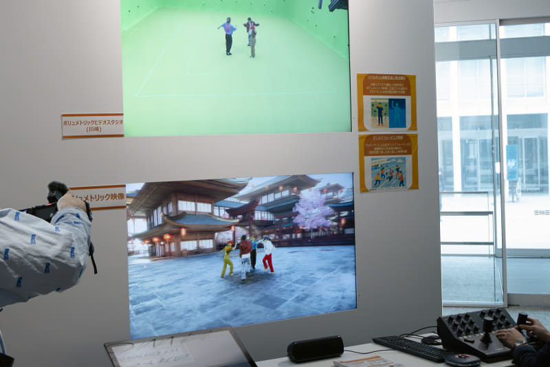 川崎市の拠点で撮影された映像の視点を右下のコントローラーで操作している。操作の情報は川崎市の拠点に送信され、背景の合成が行われる