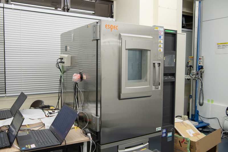 業務用冷蔵庫のようなこれが恒温室。検証では60℃まで上げたこの中にアクセスポイントを置き、その状態での内部機器の温度や、スループットなどを計測する