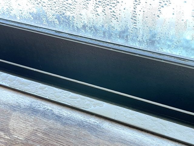 窓ガラスだけでなくアルミサッシも結露。手前の木部の黒ずみは過去に発生したカビの痕跡と思われる