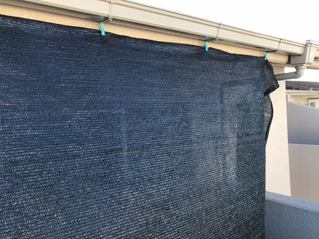 2階、東側のバルコニーで撮影。雨どいの金具を利用して洗濯バサミで吊っていた。強い風が吹くと外れる仕組み。下端にロープを付け飛ばないように構造物に結び付けていた