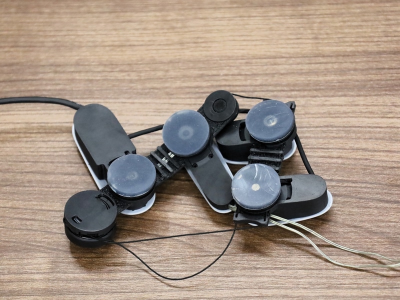 （左）装着するハプティックデバイス。（右）裏側のシリコン部分が皮膚に密着し、VRコンテンツと連動して回転することで「回転せん断刺激」が発生。あたかも腕が引っ張られたり、重さが加わったような感覚が得られる