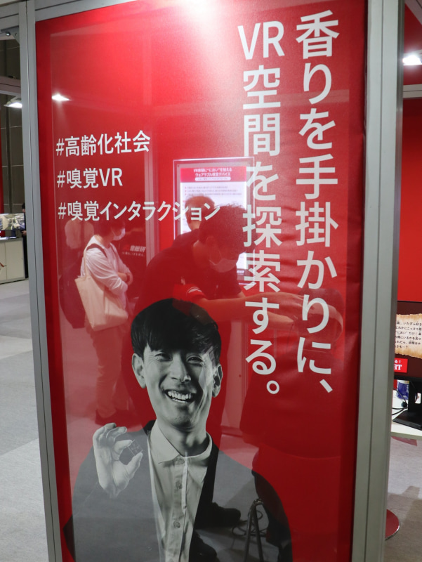 産業技術総合研究所のブース（<a href="https://www.ceatec.com/nj/exhibitor_detail_ja?id=36" class="strong bn" target="_blank">ホール4 ブース番号4H621</a>）には体験型の展示が多数。写真は、微量ガス制御による「小型ウェアラブル嗅覚ディスプレイ」とVR技術を連携させることで、人の嗅覚特性を取り込んだ高度な“匂い体験”の実現を目指す研究の展示。同ブースのそのほかの展示については、事前インタビュー記事<a href="https://internet.watch.impress.co.jp/docs/interview/2143553.html" class="strong bn" target="_blank">『「モアレ画像で“たわみ”測定」「座ったままで転倒リスク判定」「匂いが出るVR」――社会実装へ、産総研が本気の挑戦』</a>を参照してほしい