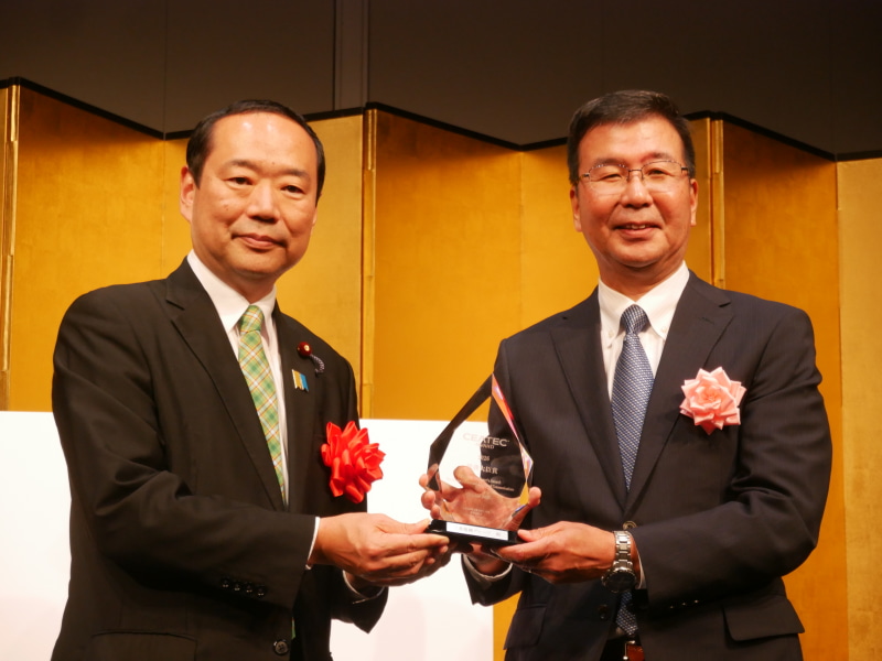 総務大臣賞を受賞した三菱電機の高澤範行副社長CSO（右）