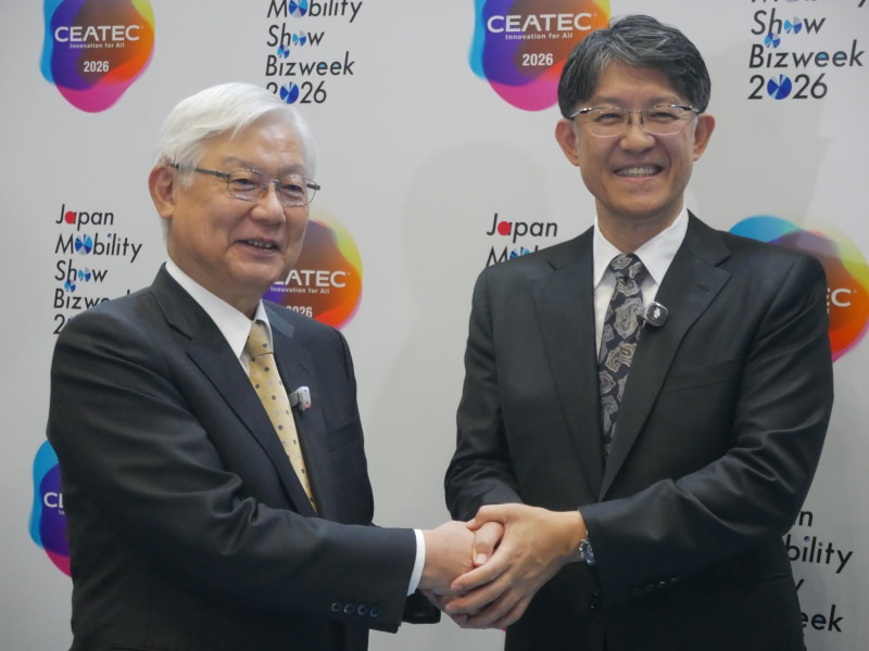 会場で握手するJEITAの新野隆会長（左）と、自工会の佐藤恒治会長（右）