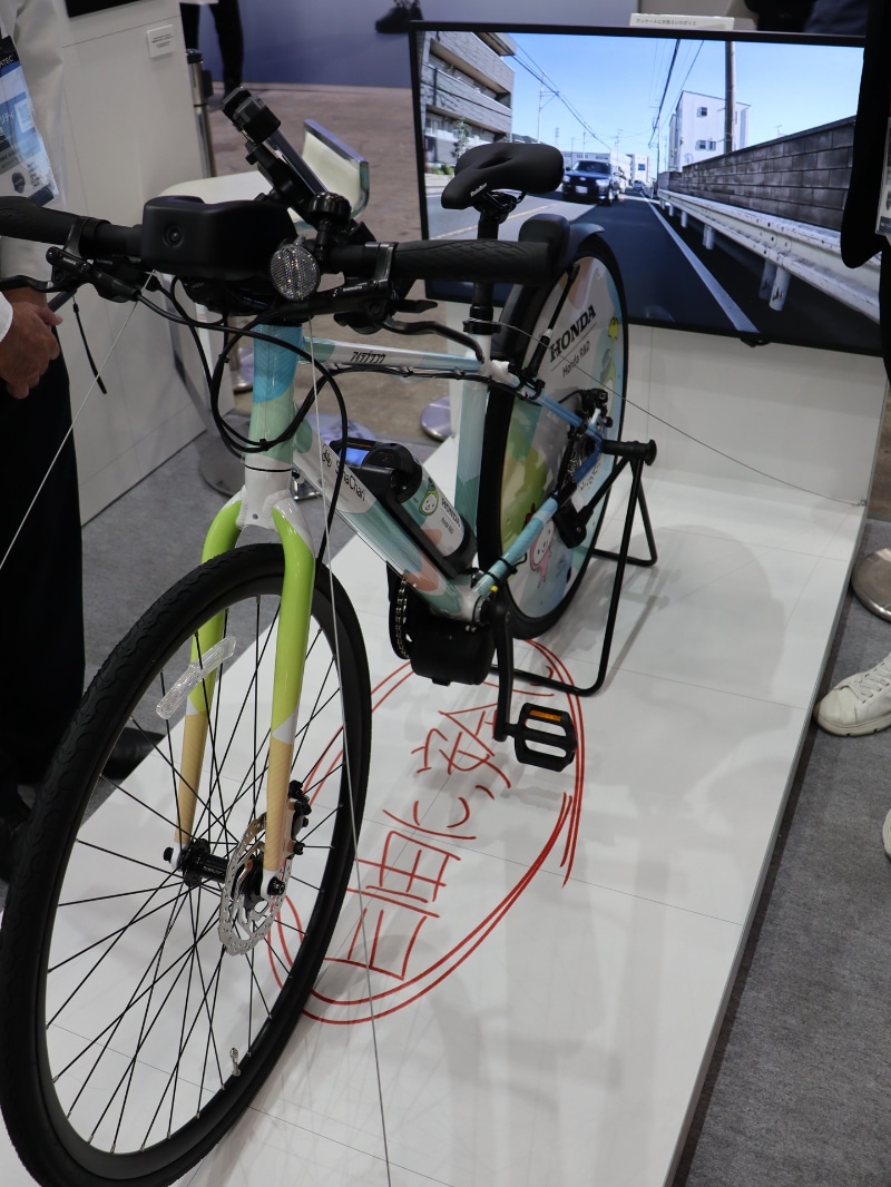 自転車やバイクに後付けできるカメラから入力される周囲の映像をもとに、CI（Cooperative Intelligence：協調人工知能）がリスクを予測し、スマートフォンでアラートを出す仕組み