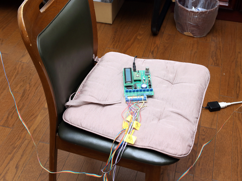 部屋の8カ所に温度センサーを設置。天井から吊り下げた4本の電線に、温度センサーを2つ、高さ違いで設置している。その温度変化は独自のデータ収集装置で記録し、パソコンに転送する