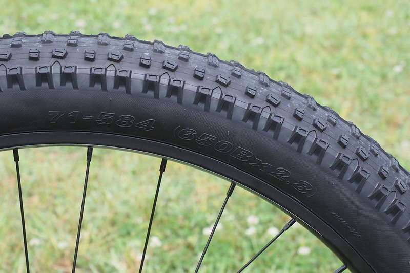 タイヤは650B×2.8というサイズで、27.5インチ径×2.8インチ幅です。左に「71-584」という刻印が見えまが、この「71」はタイヤの幅が71mm（2.8インチ）であることを示します。iPhone Xの横幅くらいあり、自転車のタイヤとしてはかなり太いです