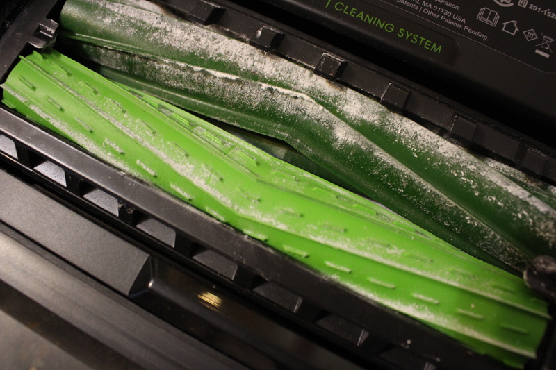 小麦粉を吸った後のデュアルアクションブラシ。濃い緑のブラシの羽根に、床からかき取った小麦粉がついている