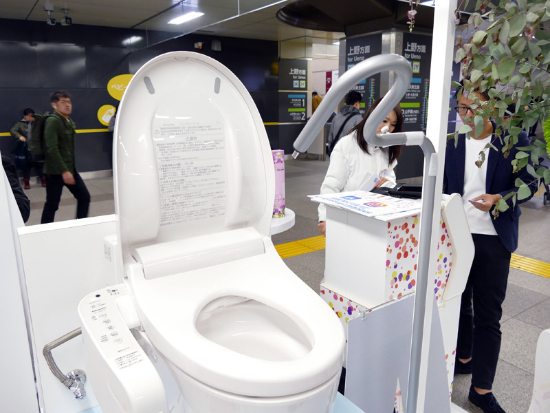 便座の斜め上から、小用を模したツールで水が投入される