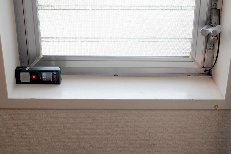 そこでレーザー測距計。一発で計測完了です♪ 写真の状態で、窓枠内側の左右端の間の距離がわかります