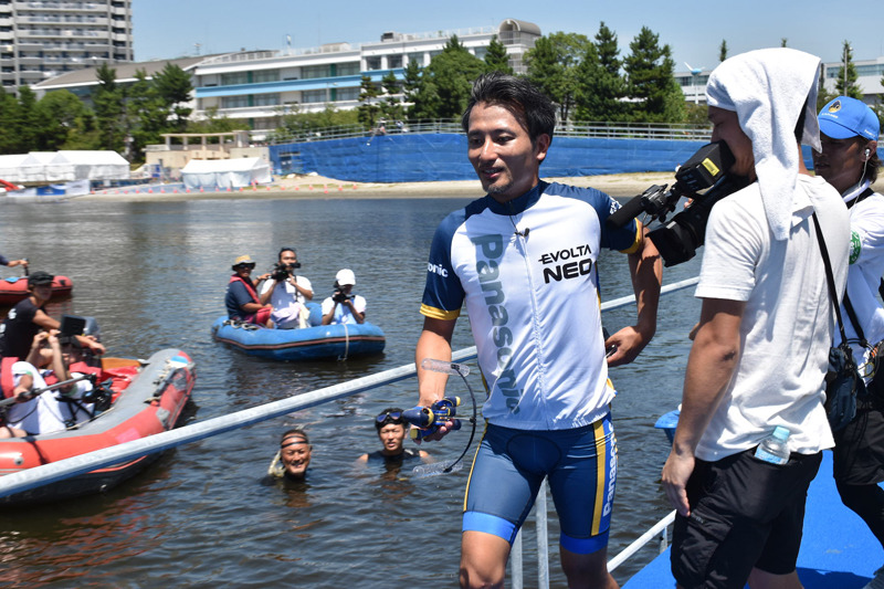 150mのスイムを終えたエボルタNEOくんを開発を務めたロボットクリエーター・高橋 智隆氏がすくい上げ、スイムからバイクへのトランジションへ走る