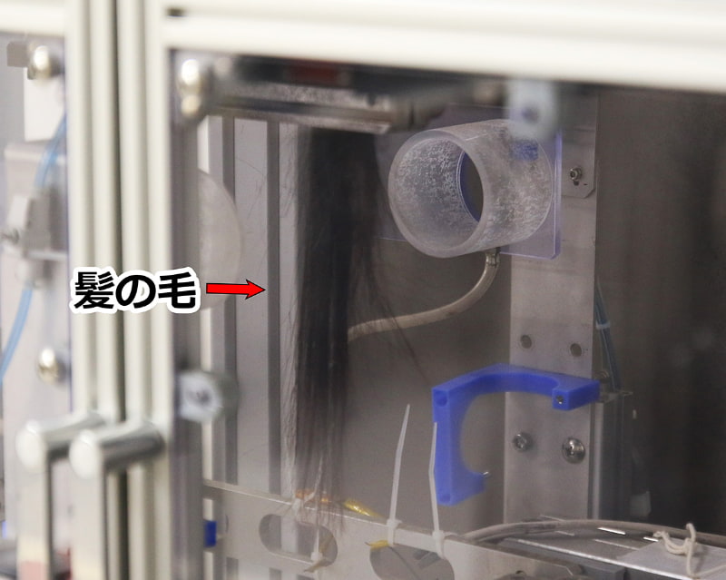 ヘアアイロンの試験機。しかし感触までは機械で測定できないので、人が手動でやる試験はなくならないという