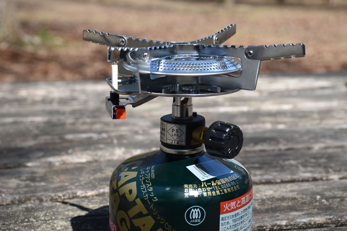 赤いボタンが点火スイッチ。黒いつまみをONの方向(←左)へ回すと火力が強くなる。慣れるとカセットコンロより手軽に使える印象
