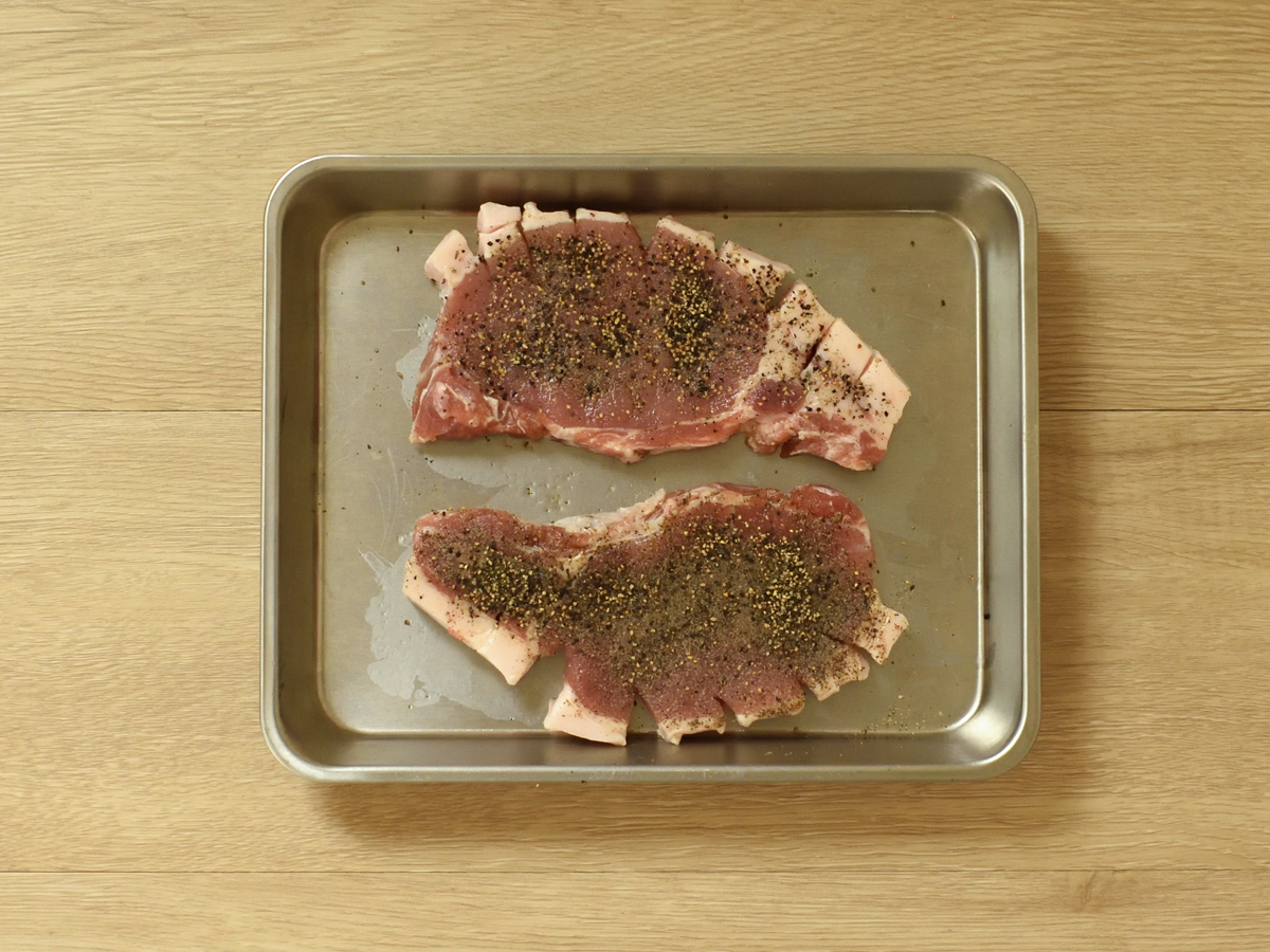 コショウをまぶしたあとに粗びき黒コショウを散らします