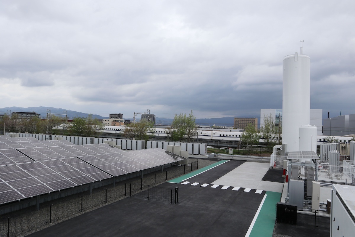 パナソニックの「Panasonic HX Kusatsu」。ずらりと並ぶ太陽光発電、奥に並ぶ白い棚のようなものが純水素型燃料電池、右側にある大きな縦型タンクが水素貯蔵用タンクだ。巨大な設備で、下り新幹線の京都駅到着5分前くらいにA席からも見えた