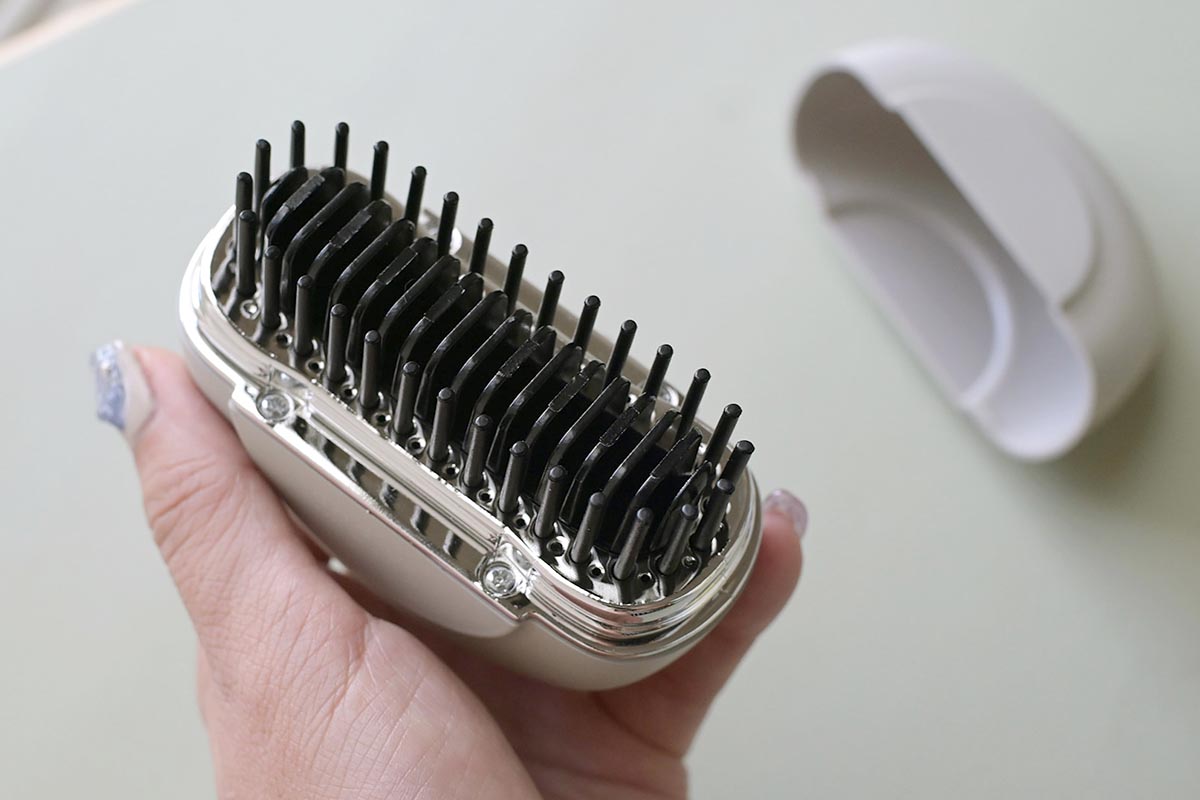 ブラシ型のヒートヘアコーム。中央に温熱プレート、周りをピンが囲むようにして配置されています