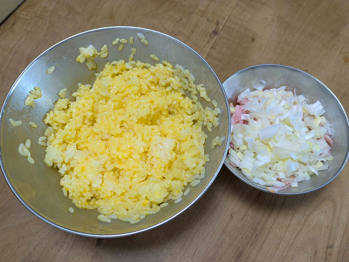 ベーコンや長ネギなどの材料を細かく切ります。ご飯はあらかじめ、溶き卵とよく混ぜておきます