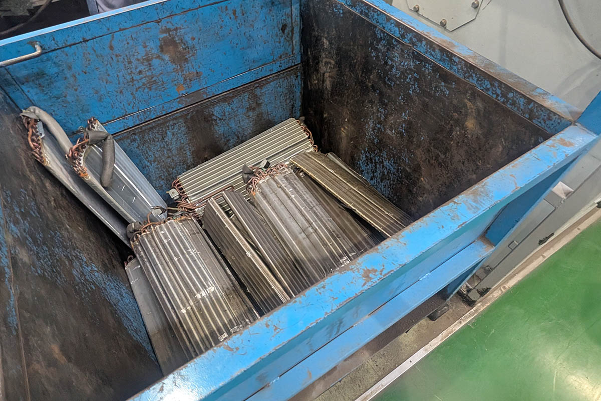 熱交換器。パナソニックのエアコンはリサイクルのことも考え、製造時のロウ付けが難しくなるが、オールアルミの熱交換器を採用している。写真の熱交換器は銅が使われているので、これを分離する必要がある