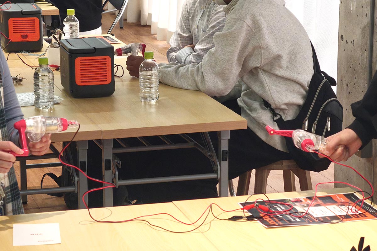 別のテーブル同士でペアを組み、手回し発電機を2台接続。片方のハンドルを回すと、もう片方のハンドルが回っていました