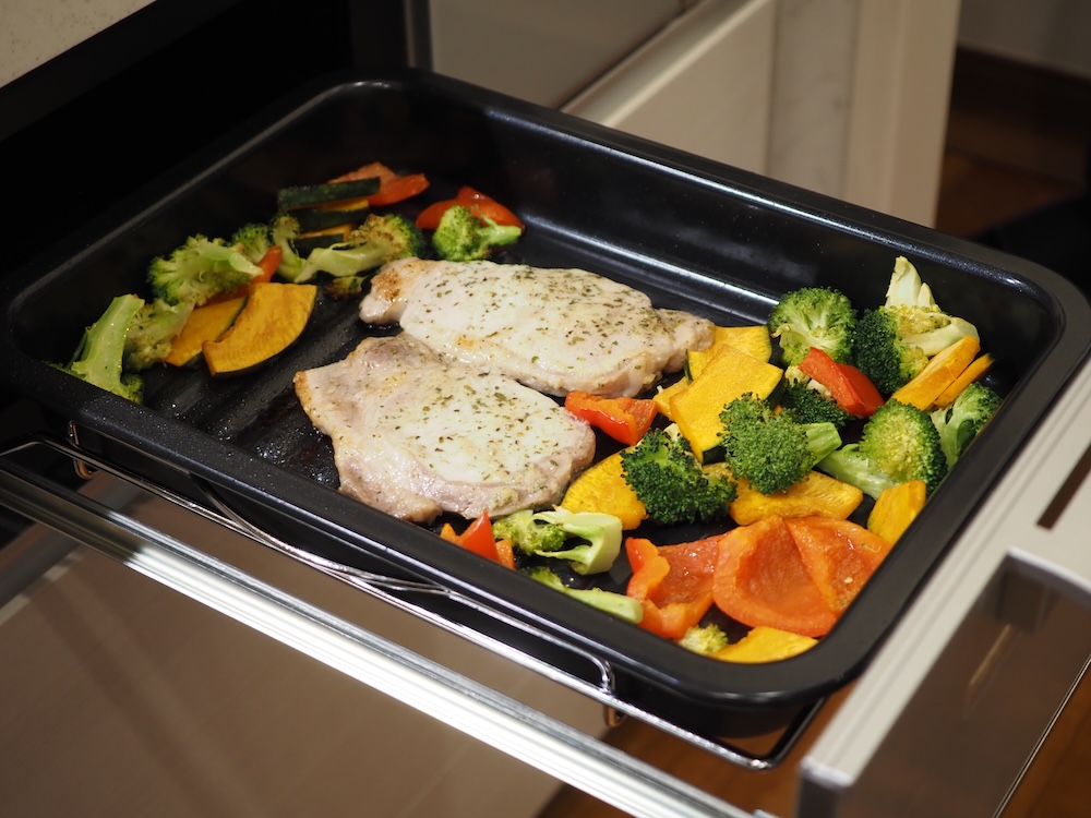 豚肩ロースと野菜などを盛ったグリル皿を、グリルにセットする