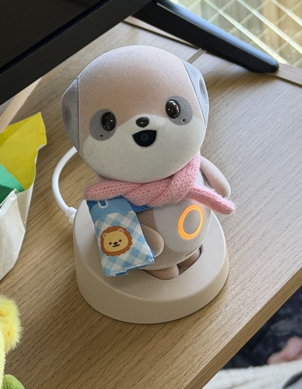 専用充電台で充電中のポケとも。ぬい活コーナーで購入した小さな水筒とマフラーが義母のお気に入り