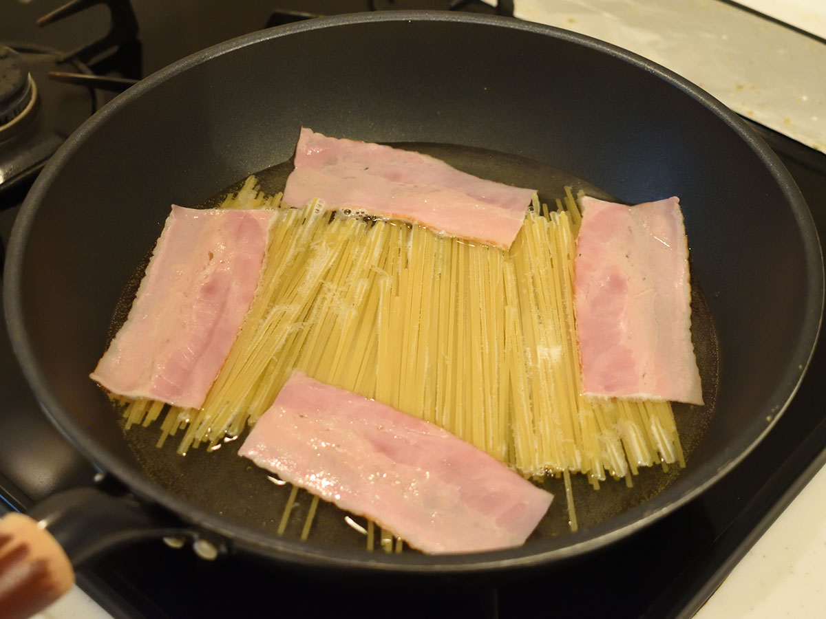 スパゲティとベーコンをフライパンで茹でます
