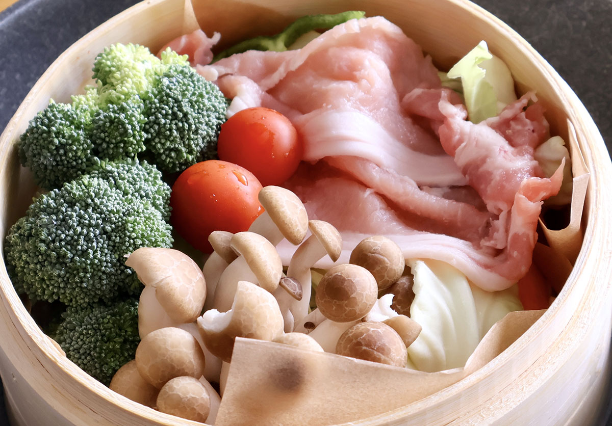 せいろにクッキングシートを敷き、カット野菜、手でちぎったブロッコリーやシメジ、ヘタを取ったミニトマト、豚ロース肉の薄切りを入れて、フタをして鍋にかけるだけ