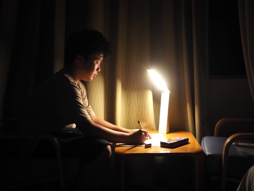 旅行先の宿でライトをつけて、突然、宿題を始めた
