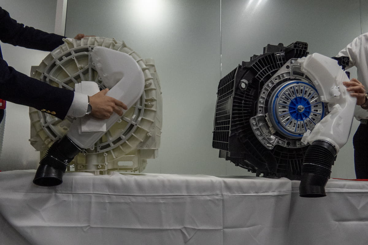 洗濯機を後ろから見たイメージで、左が新モデル、右が前モデル。乾燥風路をなだらかにすることで、風切り音や運転音の低減と送風効率アップを実現