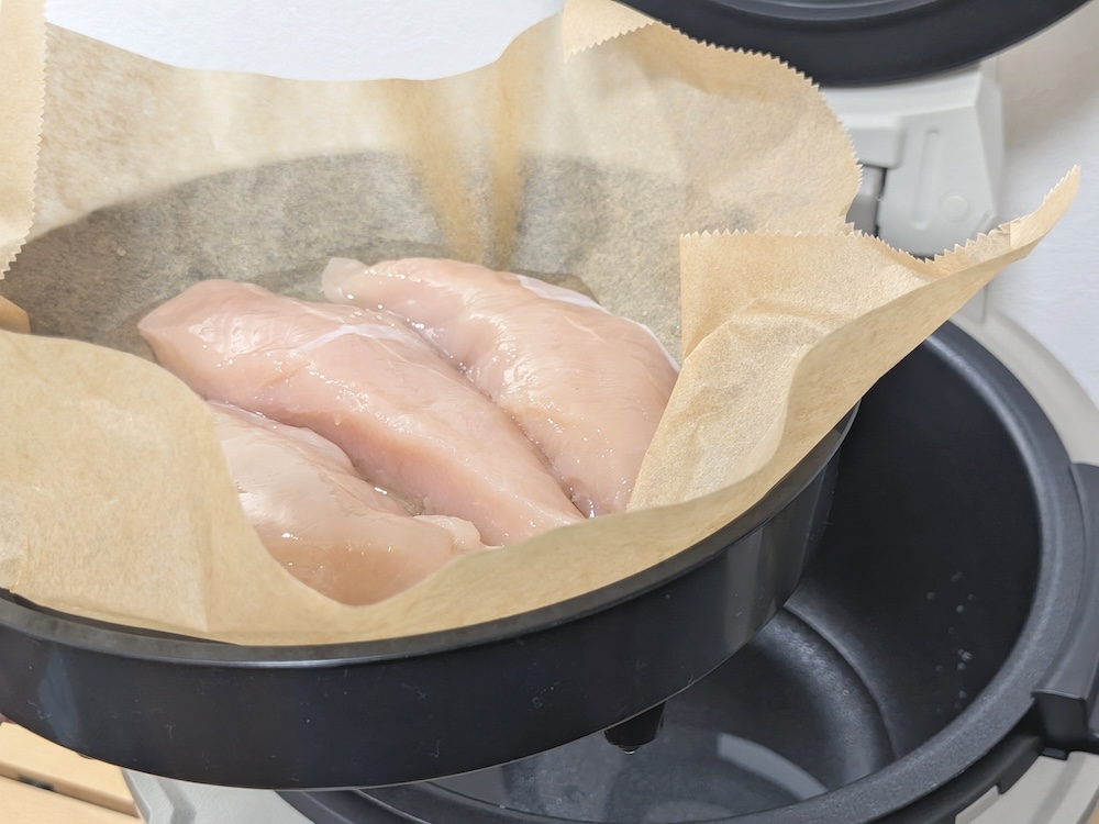 蒸しプレートにクッキングシートを敷いて、鶏肉を並べる