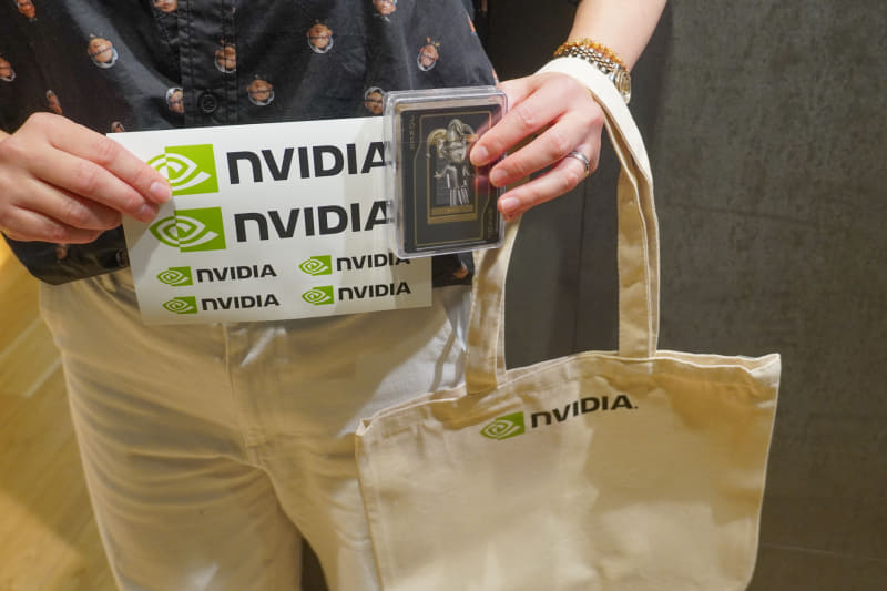今回のお土産、NVIDIAのバッグにステッカーとジェンスン・ファン氏のデザインのトランプ。手渡すNVIDIA社員はもちろんジェンスン・ファン氏のシャツを着用中