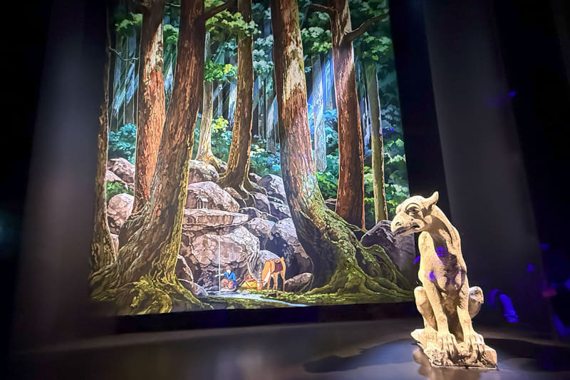 タペストリー「呪いの傷を癒すアシタカ」、森の深い緑の濃淡、木々の間から差し込む光が表現されている