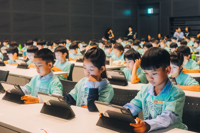 各席にタブレットがずらりと並ぶ。子供たちの真剣なまなざしが印象的