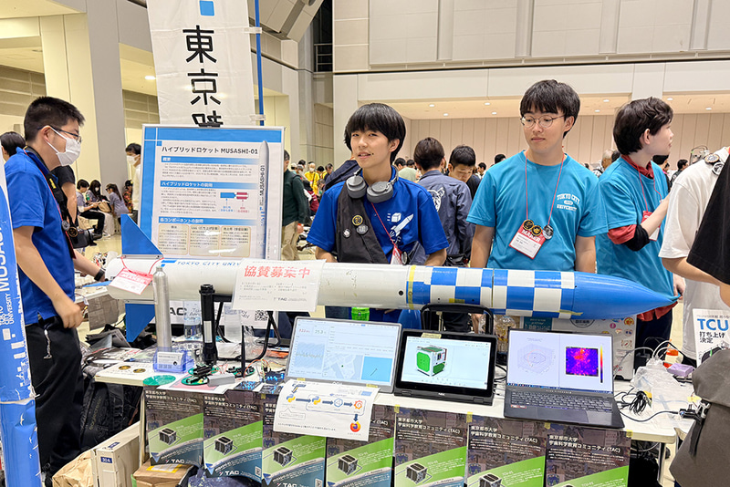 全長約2m、直径約150mmのハイブリッドロケット。現在2025年度の打ち上げを目指している。写真右は、micro:bitを使った模擬人工衛星で子供用の宇宙科学教材